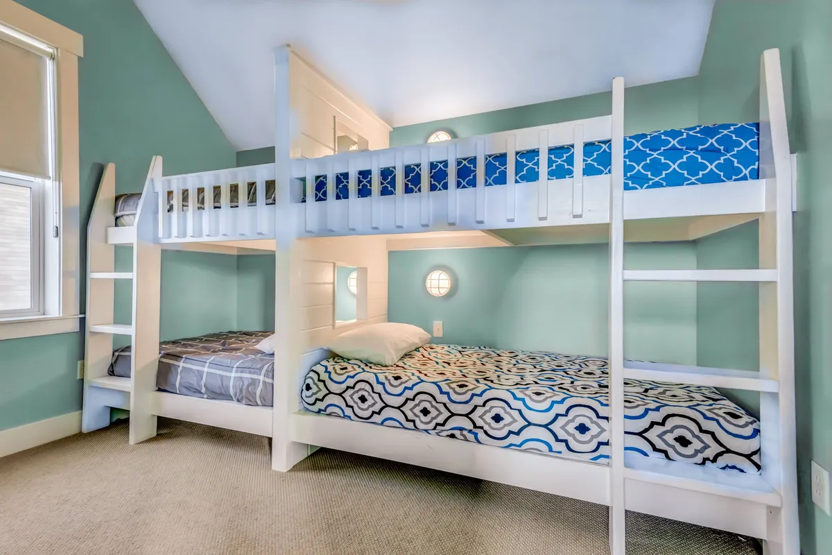 A cheerful bunk room with colorful bedding on stacked bunk beds, playful wall color, and a cozy atmosphere. The arrangement invites children to climb, play, and enjoy bedtime stories, making the room feel like a fun sleepover spot.